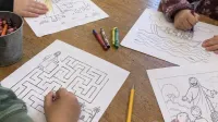 Niños realizando actividades bíblicas en una mesa de catequesis
